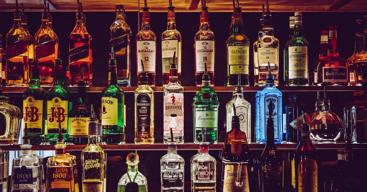 An array of various liquor bottles beautifully displayed on a bar shelf.