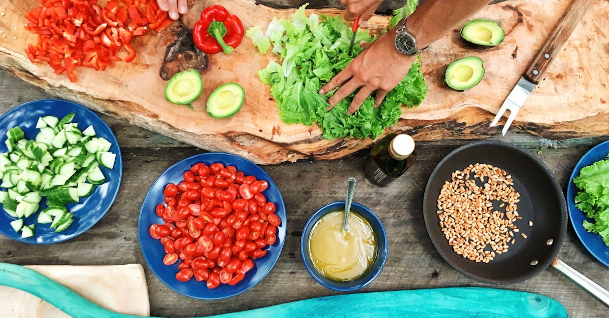 Fresh ingredients being prepared on a rustic wooden table, showcasing vibrant vegetables and hands at work.